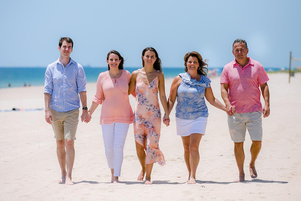 family walking on the beach during gender reveal photoshoot family walking on the beach during gender reveal photoshoot