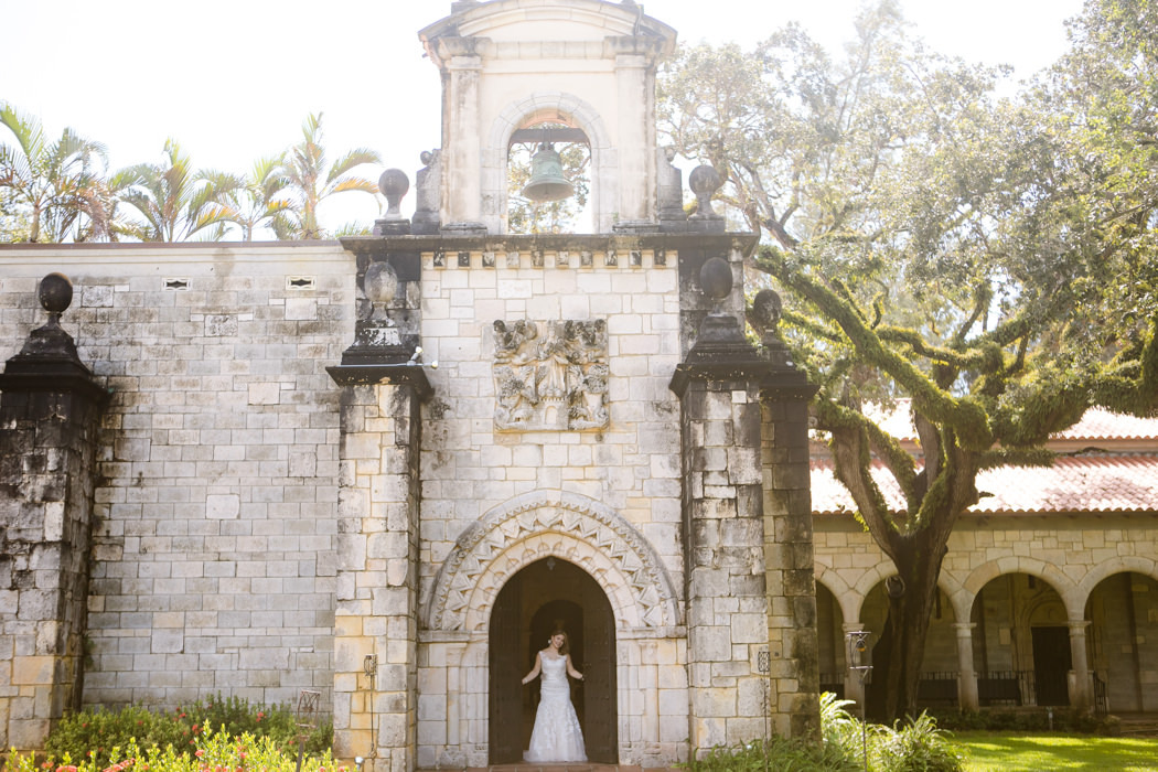 bride poses at wooden doors of miami wedding venue | ancient spanish monastery
