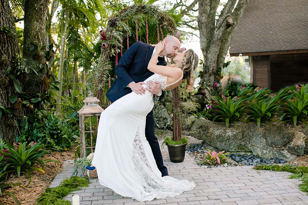 groom dips the bride | modern wedding at living sculpture sanctuary davie | floral wedding arch
