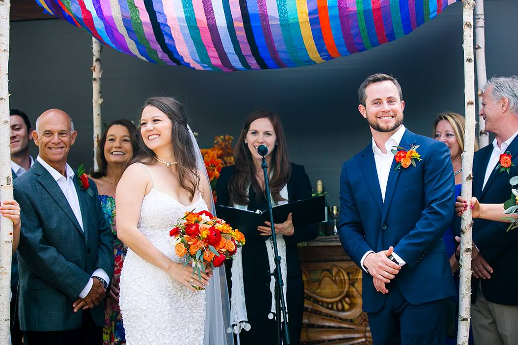 jewish bride and groom under colorful handmade chuppah at wedding ceremony, east hotel miami