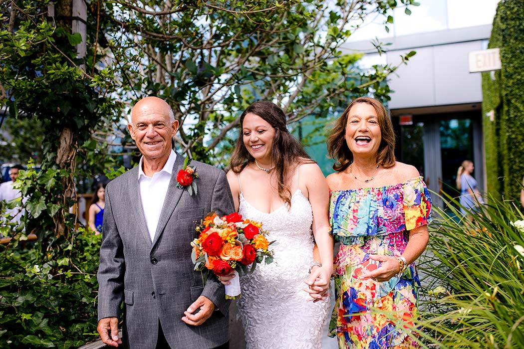 jewish brides parents laugh as they walk her down the aisle at east hotel miami