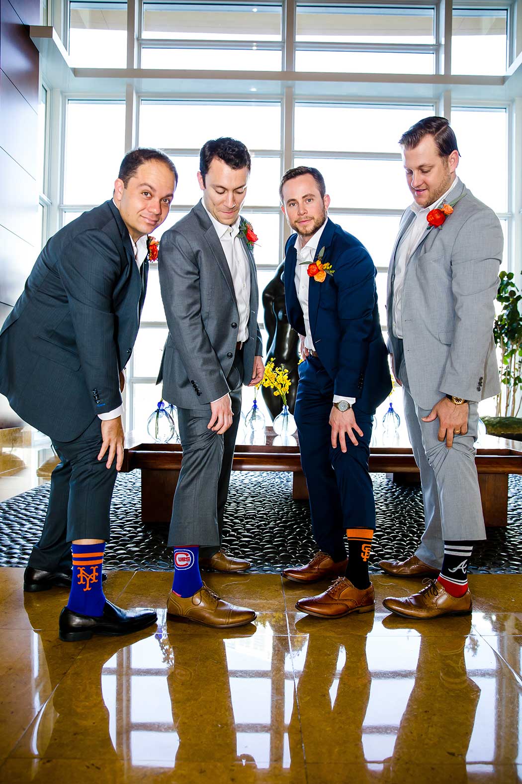 modern jewish wedding at east hotel miami | groomsmen showing their wedding socks to photographer