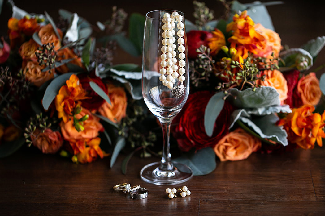 beautiful wedding details shot with pearl necklace, bouquet and champagne glass