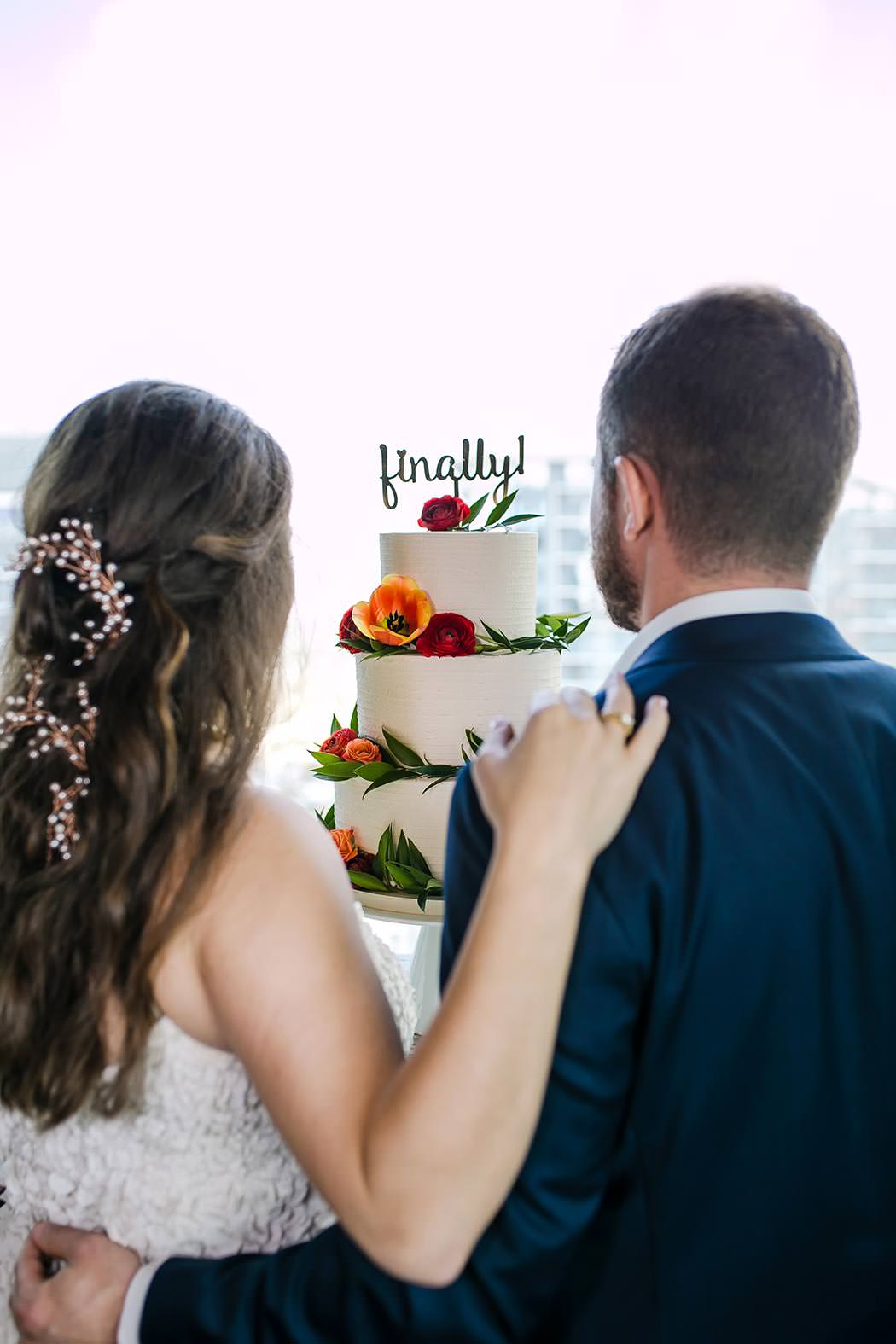 modern wedding cake with orange and red flowers and funny wedding cake topper | east hotel miami wedding