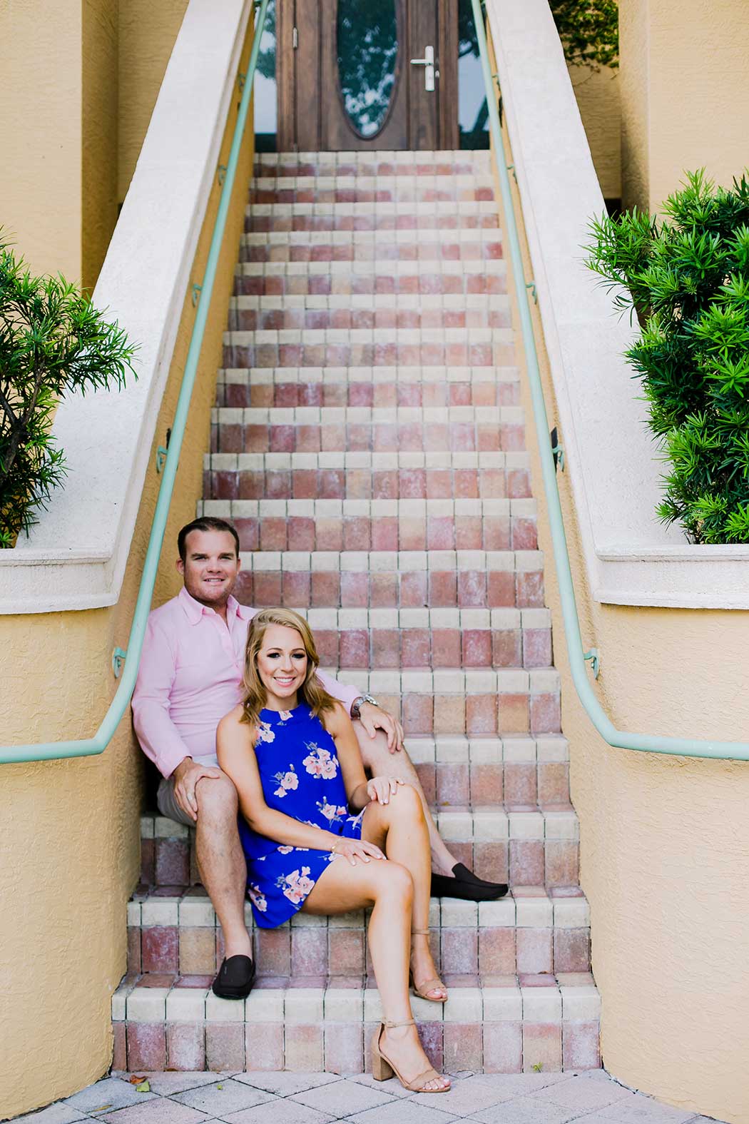 couple posing on stairway for engagement photoshoot | blue floral dress