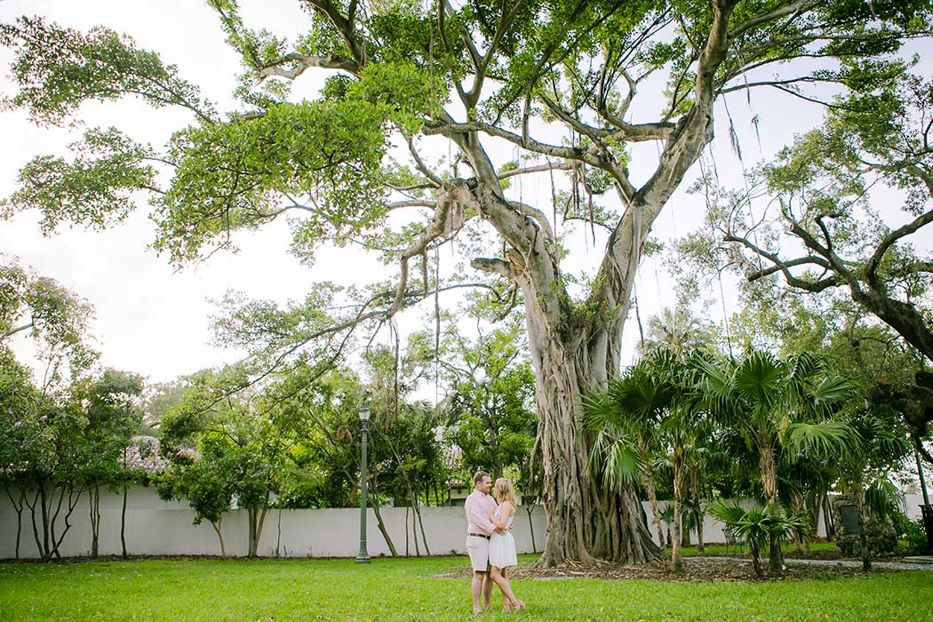 couple posing for engagement photos under large hammock tree in fort lauderdale