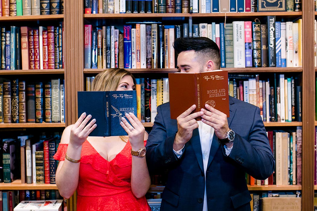couple posing behind some antique books for their engagement session in fort lauderdale