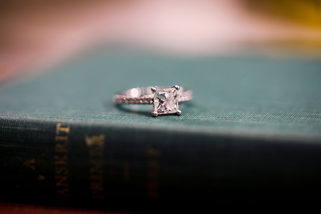 square diamond engagement ring is photographed on an antique book during engagement session