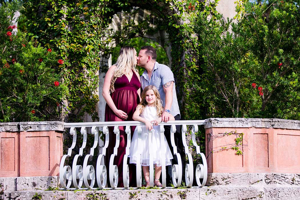 couple posing for maternity photoshoot at vizcaya miami with young daughter