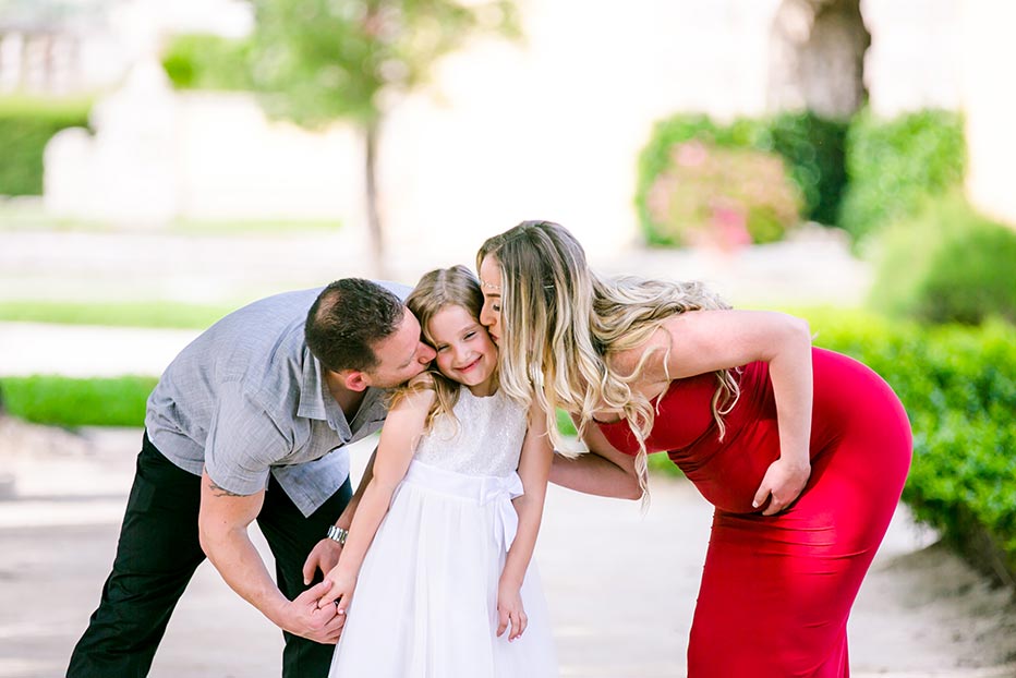 family photoshoot at vizcaya miami | mother and father kiss daughter family maternity photoshoot at miami's vizcaya | red maternity dress | kissing daughter
