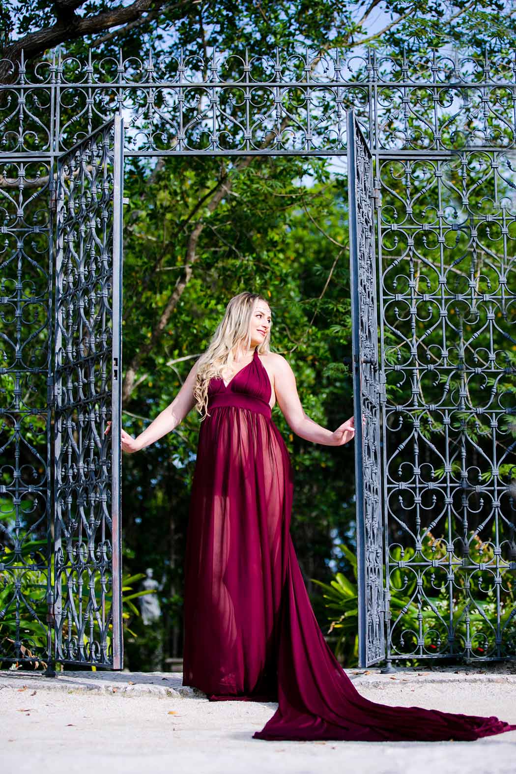 long dark red maternity dress | maternity photoshoot with iron gate maternity photoshoot with iron gate | long dark red maternity dress | vizcaya maternity session