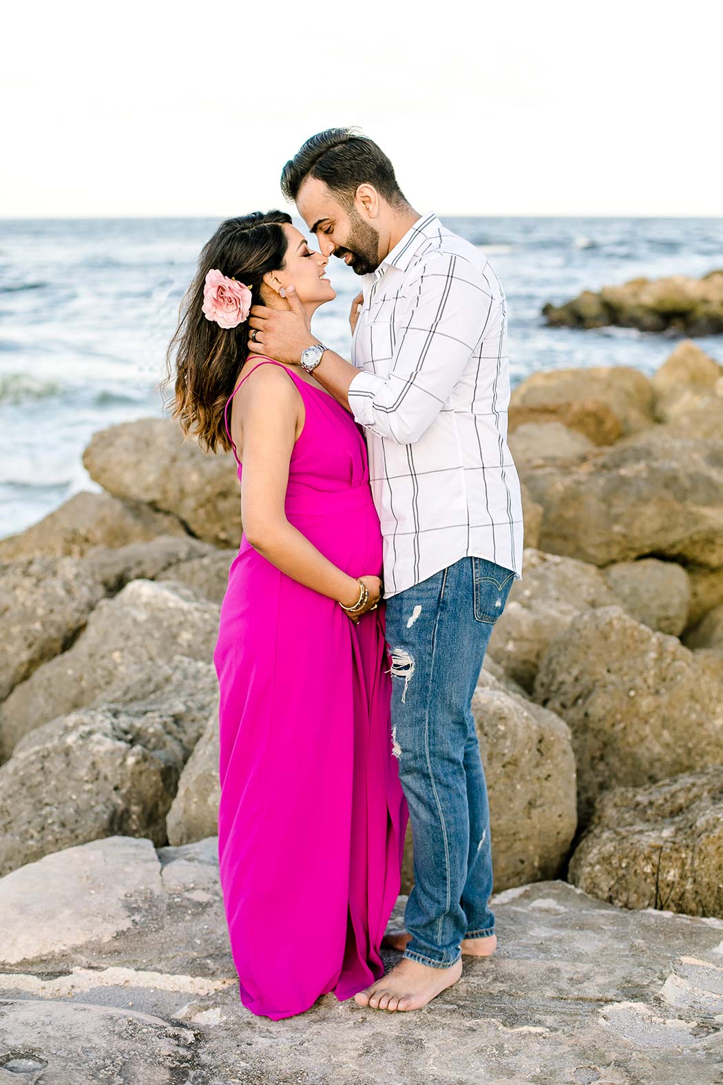 beautiful girl posing for beach maternity photos in pink maternity dress