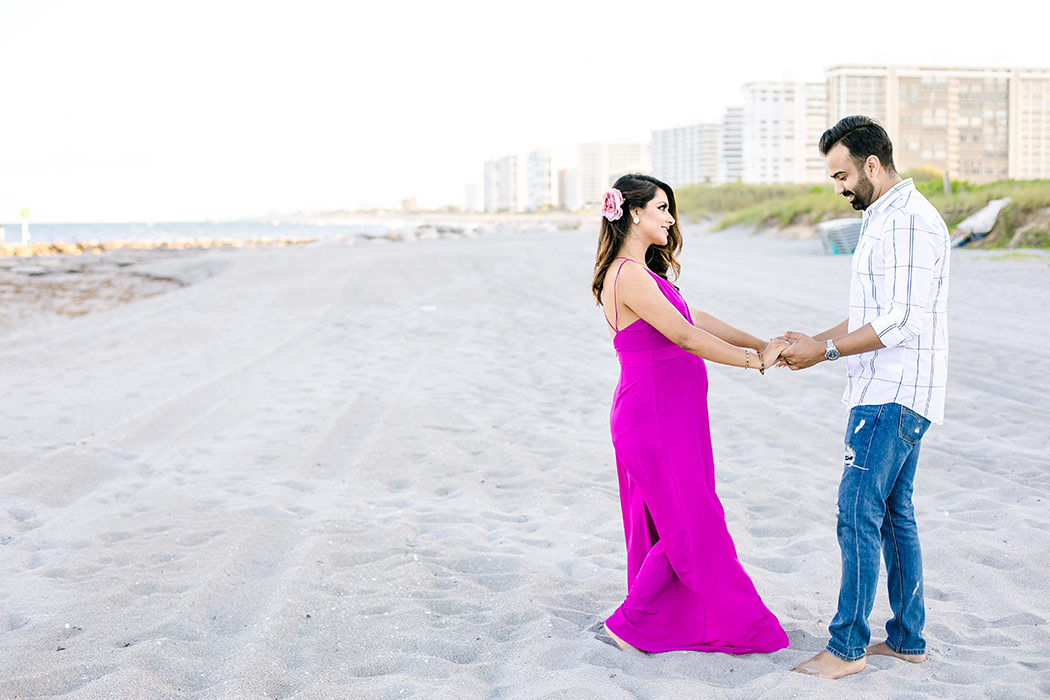 girl in pink maternity dress dances with husband on beach during beach maternity session in boca raton