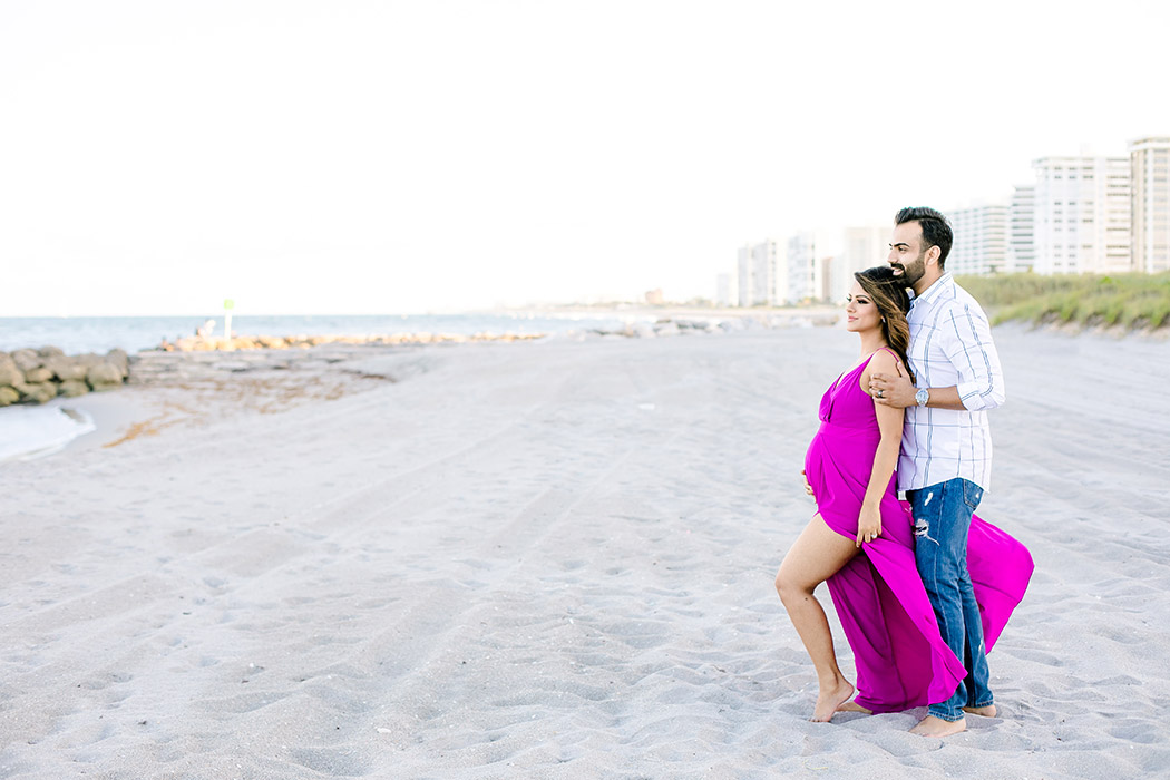 beach maternity photoshoot with couple looking out to sea | pink maternity dress