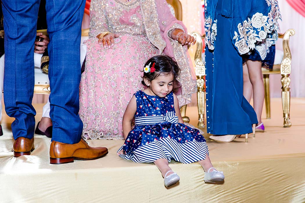 little indian girl in blue and white dress on the stage of indian bride and groom wedding reception
