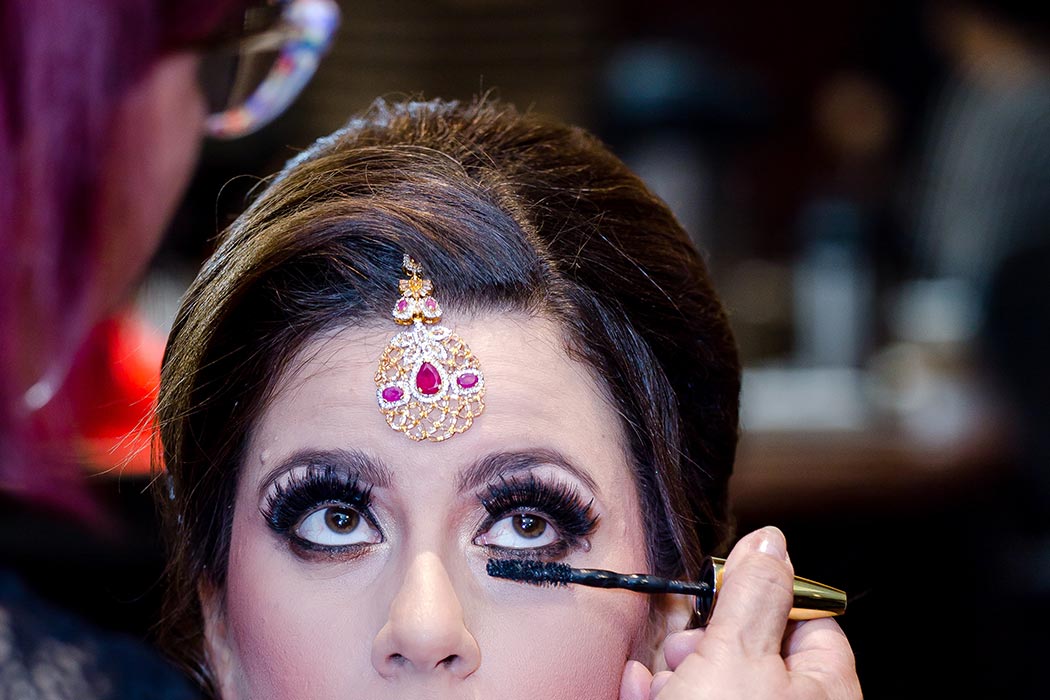 indian bride having her makeup done before her muslim indian wedding ceremony