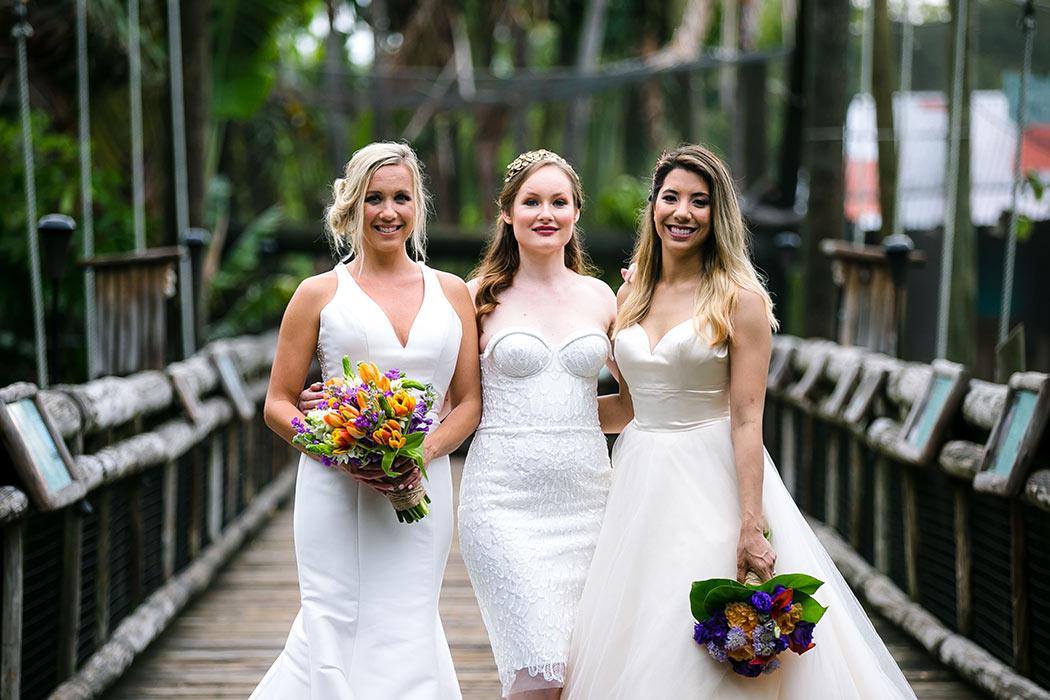 three brides posing on wooden bridge at palm beach zoo styled wedding