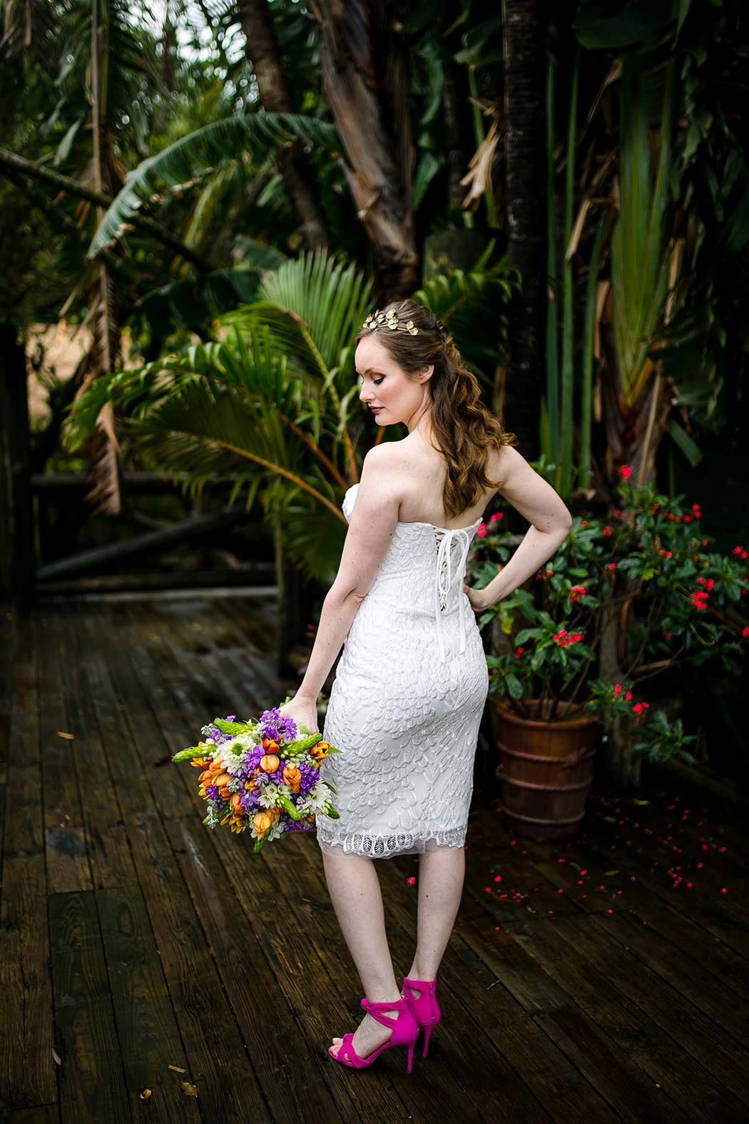 bride poses in modern short wedding dress with a purple and orange wedding bouquet at palm beach zoo