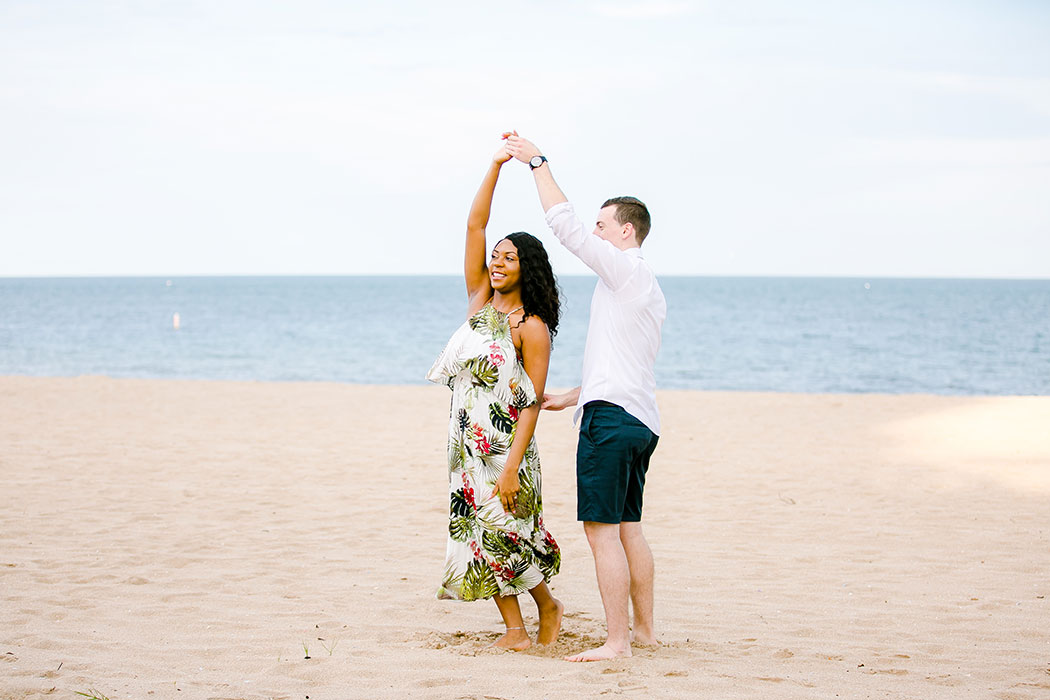 mixed race couple dancing on pompano beach during engagement photoshoot | beach engagement photographer south florida