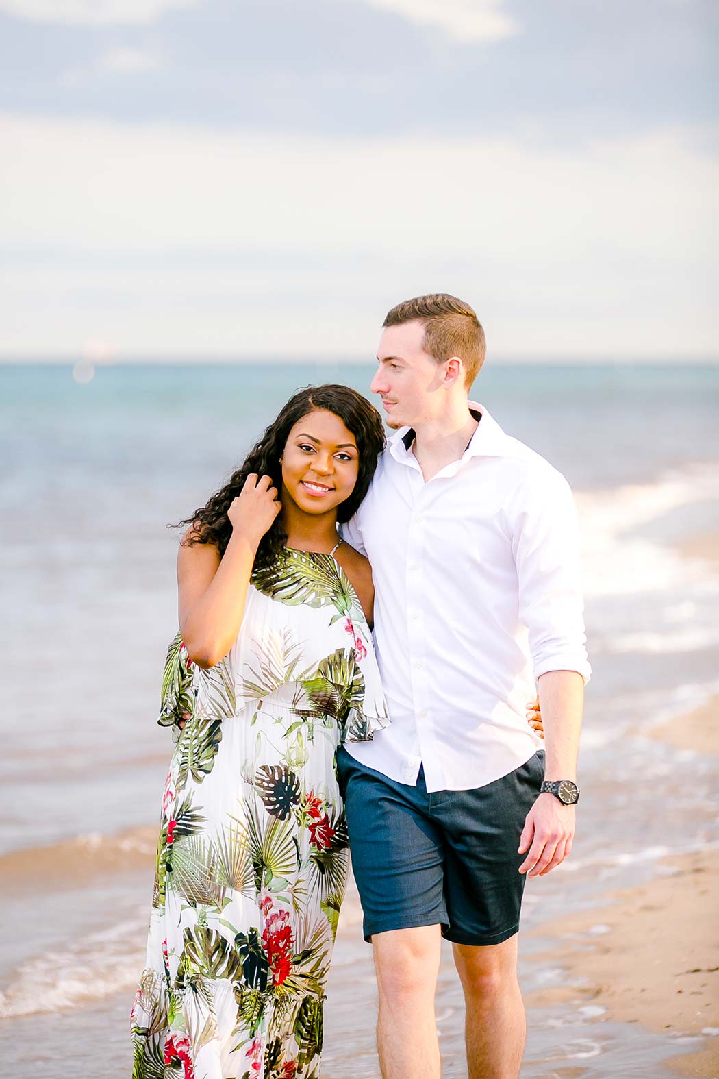 beautiful mixed race couple walking on beach for engagement photoshoot