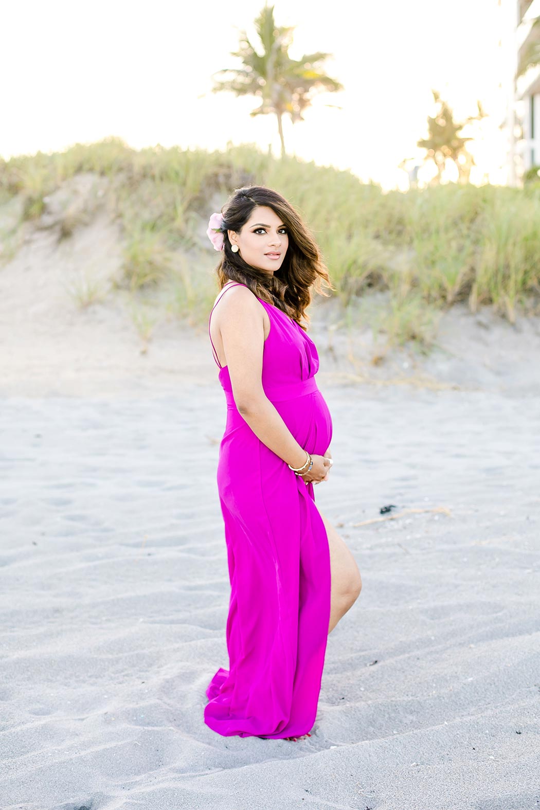 beautiful girl posing for beach maternity photo shoot in south florida wearing pink maternity dress